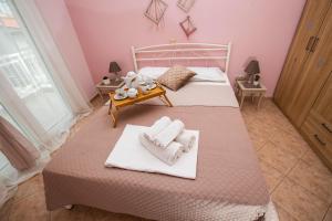 a pink bedroom with a bed with towels on it at House Stella in Keramotí