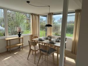 a dining room with a table and chairs and windows at Weststrandhaus in Großenbrode