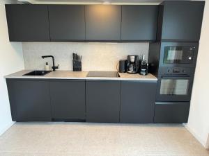 a kitchen with black cabinets and a sink at Weststrandhaus in Großenbrode