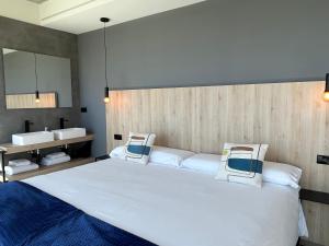 1 dormitorio con 1 cama blanca grande y 2 lavabos en Hospedium Hotel Devalar Do Mar en Camariñas