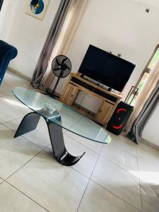 ein Wohnzimmer mit einem Glastisch und einem TV in der Unterkunft Perchment view Apartment in Lusaka