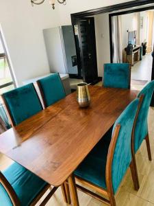 drewniany stół z niebieskimi krzesłami i wazonem na górze w obiekcie Perchment view Apartment w mieście Lusaka
