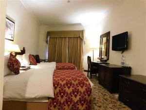 a hotel room with a bed and a desk and a television at Islamabad Lodges in Islamabad