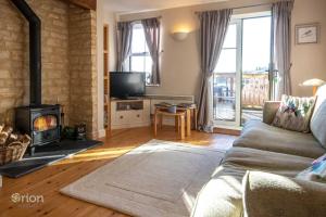 a living room with a couch and a fireplace at Mill Village 81, Trout Cottage in Somerford Keynes
