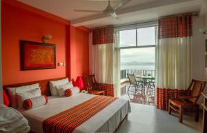 a bedroom with orange walls and a bed and a balcony at Villa Baywatch, Rumassala in Unawatuna +69 photos