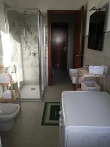 een badkamer met een douche en een witte koelkast bij I Corbezzoli in Porto Torres