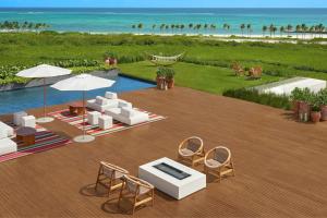 a deck with chairs and a pool and the beach at The Riviera Maya EDITION at Kanai in Playa del Carmen