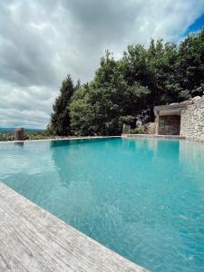 a large swimming pool with blue water and trees at Casa do Cebro Casa con piscina y jacuzzi privados in Santiago de Compostela