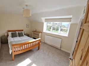 um quarto com uma cama de madeira e uma janela em Rosemary Cottage, Uley, Gloucestershire em Uley