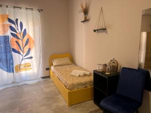 a small bedroom with a bed and a chair at Pura Vida Apartment in Catania