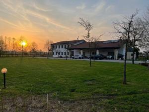 una casa en un campo con la puesta de sol en el fondo en Agriturismo Al Botteniga en Treviso