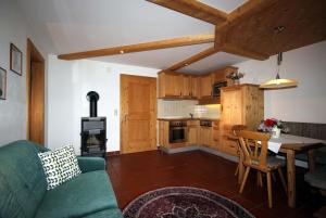 Una sala de estar con un sofá verde y una cocina. en Appartement Evi, en Kals am Großglockner