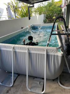 un homme dans une piscine avec un chien dans l'eau dans l'établissement Rumah Hijau Homestay, à Alor Setar