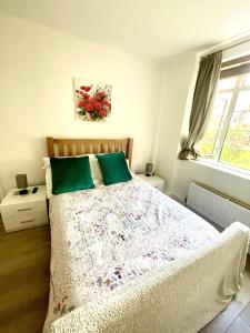 ein Schlafzimmer mit einem Bett mit grünen Kissen und einem Fenster in der Unterkunft Impeccable 2-Bed Apartment in London in London