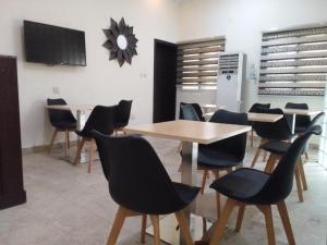 a dining room with tables and chairs and a tv at st Theresers apartment B2 in Lekki