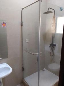 una ducha con una puerta de cristal junto a un lavabo en st Theresers apartment B2, en Lekki
