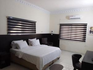 1 dormitorio con 1 cama con sábanas y almohadas blancas en st Theresers apartment B2, en Lekki