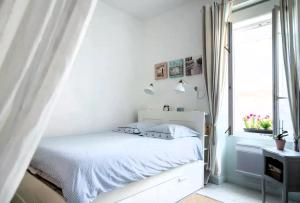ein weißes Schlafzimmer mit einem Bett und einem Fenster in der Unterkunft La Maison de la Plage in Les Sables-dʼOlonne