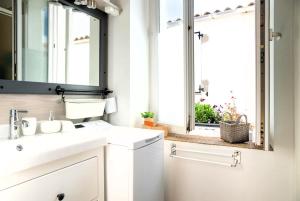 ein Bad mit einem Waschbecken, einem Spiegel und einem Fenster in der Unterkunft La Maison de la Plage in Les Sables-dʼOlonne