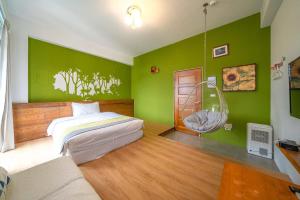 a bedroom with green walls and a bed and a swing at Field Trail Homestay in Jiaoxi