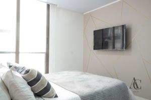 a bedroom with a bed with a tv on the wall at AC - Living 58 - Chapinero - Apartasuites in Bogotá