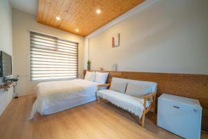 a bedroom with a bed and a chair and a window at Field Trail Homestay in Jiaoxi