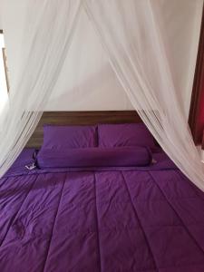 ein Bett mit violetter Bettwäsche und einem Baldachin in der Unterkunft Grand Luxe Kamala in Kamala Beach