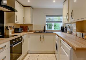 a kitchen with white cabinets and a sink at Dolphin Cottage in Wiveton