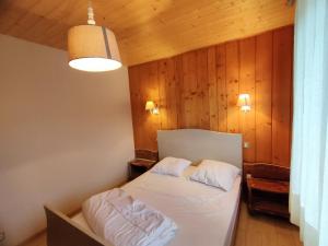 1 dormitorio con 1 cama en una habitación con paredes de madera en Sur Les Hauteurs du Lac, proche pistes en Gérardmer