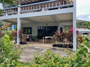 ein Haus mit einer Terrasse mit Pflanzen davor in der Unterkunft Grand Luxe Kamala in Kamala Beach