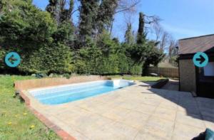 a small swimming pool in a yard with a house at Aldridge in Chipstead