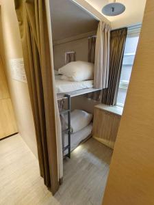 日初青旅 Sundaily Hostel 北車 في تايبيه: غرفة صغيرة فيها سرير ووسائد