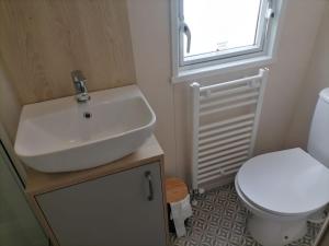 uma casa de banho com um lavatório e um WC em The Willows - 3 bedrooms with enclosed decking em Fairlight