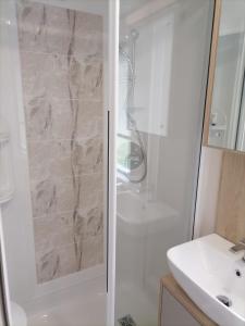 uma casa de banho com um chuveiro e um lavatório. em The Willows - 3 bedrooms with enclosed decking em Fairlight