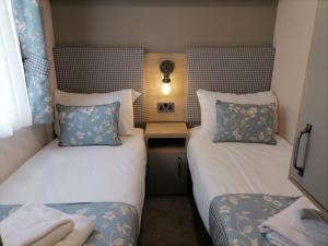 um pequeno quarto com duas camas e uma mesa em The Willows - 3 bedrooms with enclosed decking em Fairlight