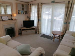a living room with a couch and a television at The Willows - 3 bedrooms with enclosed decking in Fairlight