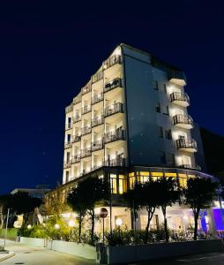 um edifício alto à noite com árvores em frente em B&B Via Mare em Milano Marittima