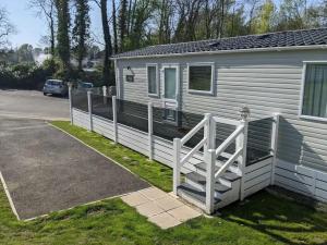 a white fence next to a white trailer at The Willows - 3 bedrooms with enclosed decking in Fairlight
