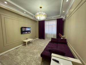 uma sala de estar com um sofá roxo e uma televisão em Комфортная квартира в ЖК ГРИН ПЛАЗА em Aktau