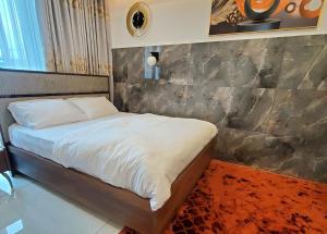 - une chambre avec un lit et un mur en pierre dans l'établissement Cozy Ghana Airport Studio at Kass Towers, à Accra