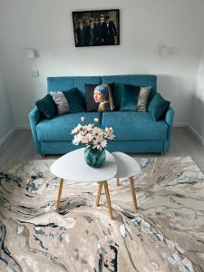 a woman sitting on a blue couch in a living room at LA PARENTHESE in Tournai