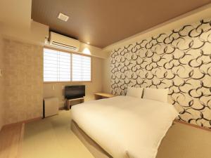 ein Schlafzimmer mit einem weißen Bett und einer Wand in der Unterkunft Asakusa Hotel Hatago in Tokio