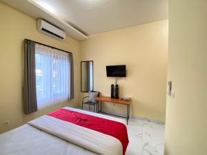 a bedroom with a bed and a desk with a television at RedDoorz Syariah near Alun Alun Purwokerto 3 in Purwokerto