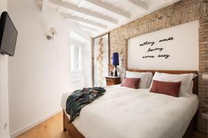 a bedroom with a white bed with a brick wall at Idyllia - Cozy central retreat in Trastevere in Rome
