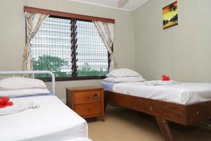two twin beds in a room with a window at Gizo Lodge in Gizo