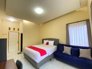 a bedroom with a bed and a blue couch at RedDoorz Syariah near Alun Alun Purwokerto 3 in Purwokerto