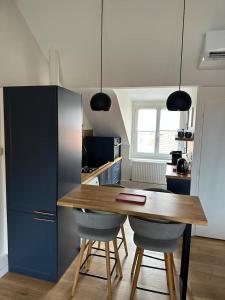 cocina con mesa de madera y armarios azules en Superbe appartement plein centre de Biarritz, en Biarritz