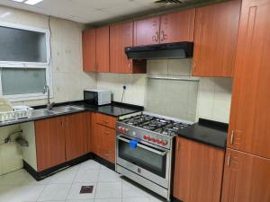 una cucina con armadi in legno e piano cottura. di شقة فخمة وواسعة غرفتين luxury and big 2BR ad Ajman