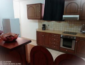 eine Küche mit Holzschränken, einem Tisch und einem Kühlschrank in der Unterkunft Geralis Lodge in Chalkida