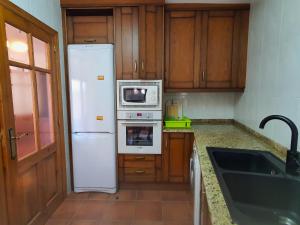 cocina con nevera blanca y microondas en APARTAMENTOS EL PORTAL, en Mora de Rubielos